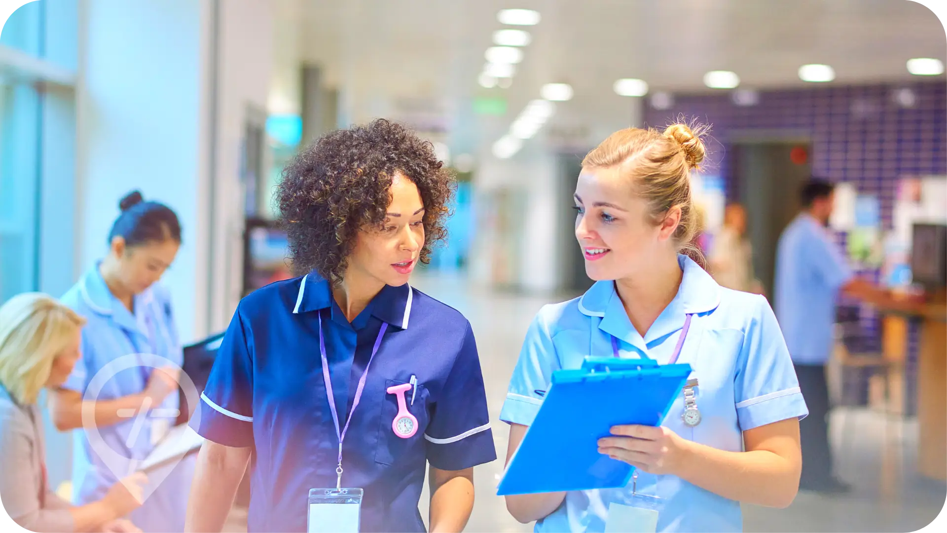 Two nurses engaged in a professional conversation while reviewing a patient file inside a hospital facility.
